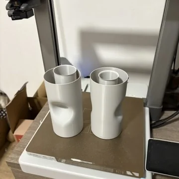 Two 3D printed white vase forms on a workbench