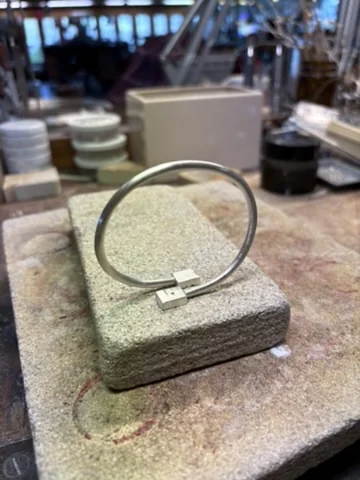 Unfinished silver bangle on a soldering block