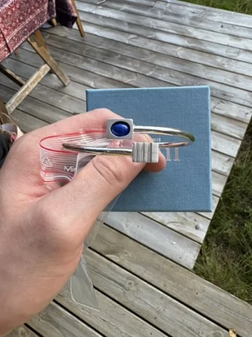 Finished bracelet held in hand next to its gift box, outdoors