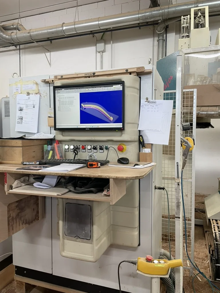 CAD model of the curved bracket shown on the CNC workstation screen
