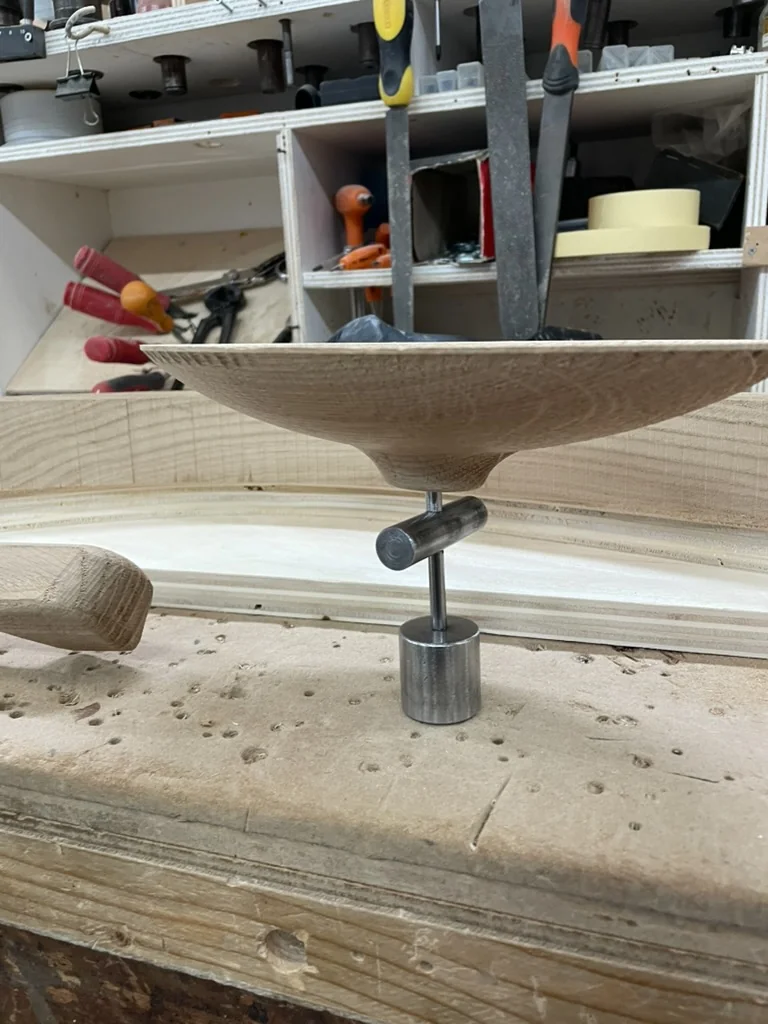 Finished wood bowl balanced on its metal pivot, testing the tilt