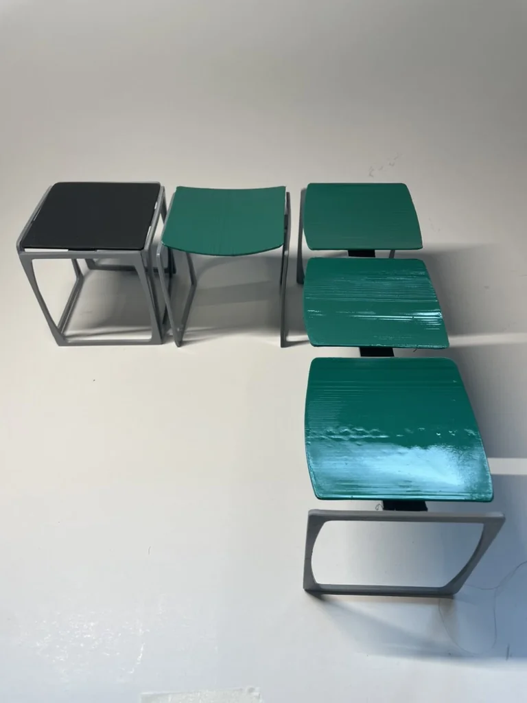 Several 3D printed Kart seat models lined up, some with warped green paint from sun exposure