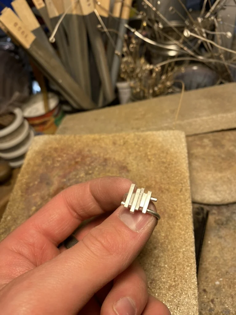 Holding the finished silver ring with vertical bars
