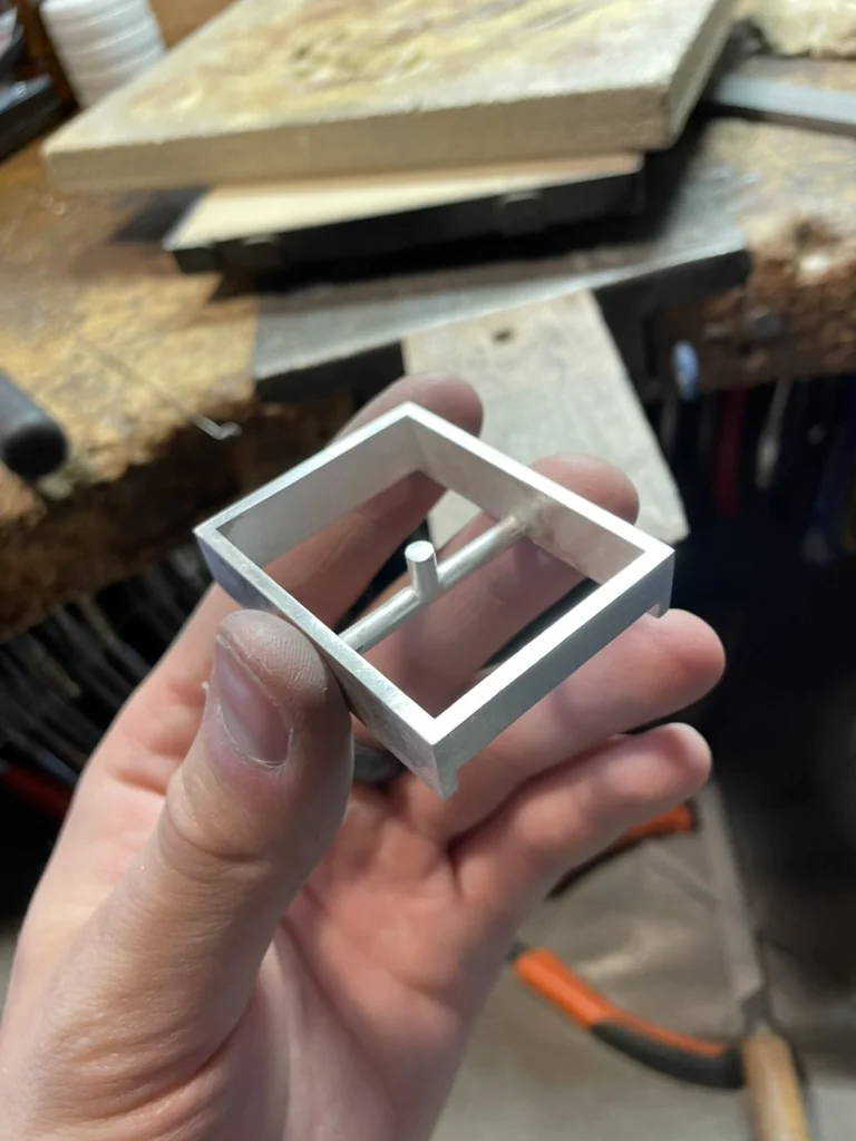 Holding the unfinished silver buckle frame with a soldered pin inside