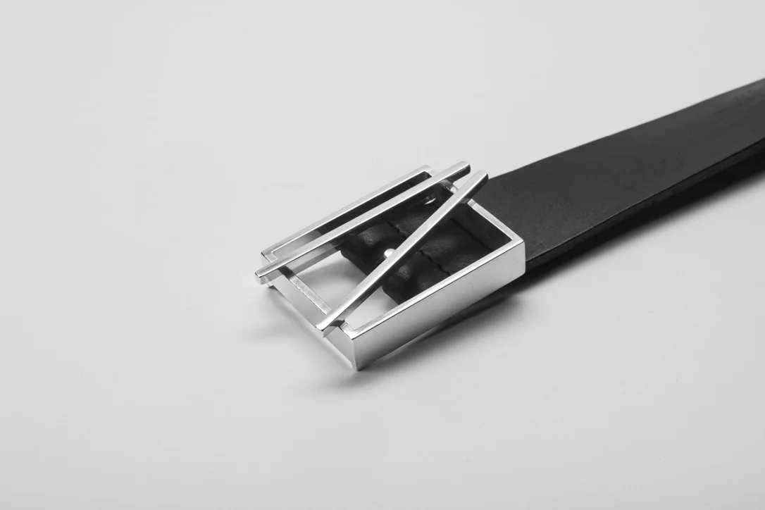 Finished polished silver buckle on the black leather belt, angled view